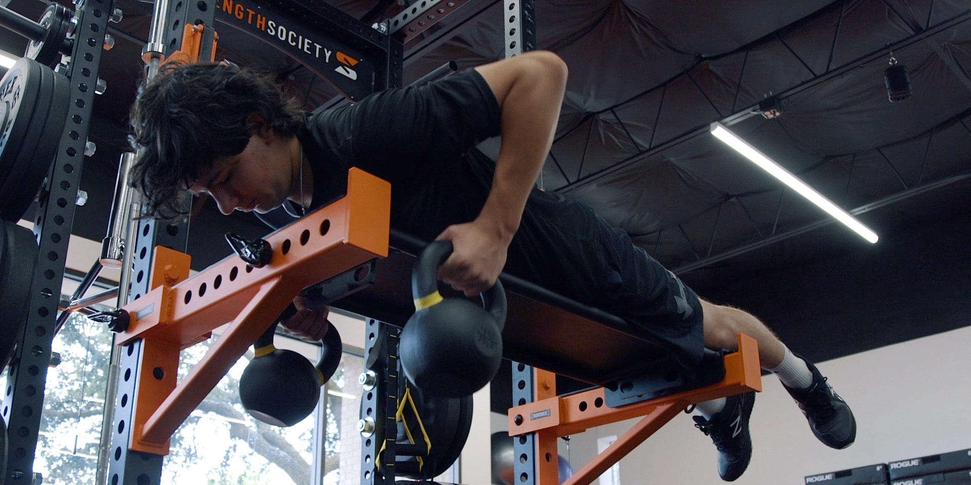 Strength Society man Training Kettlebell Lying Row